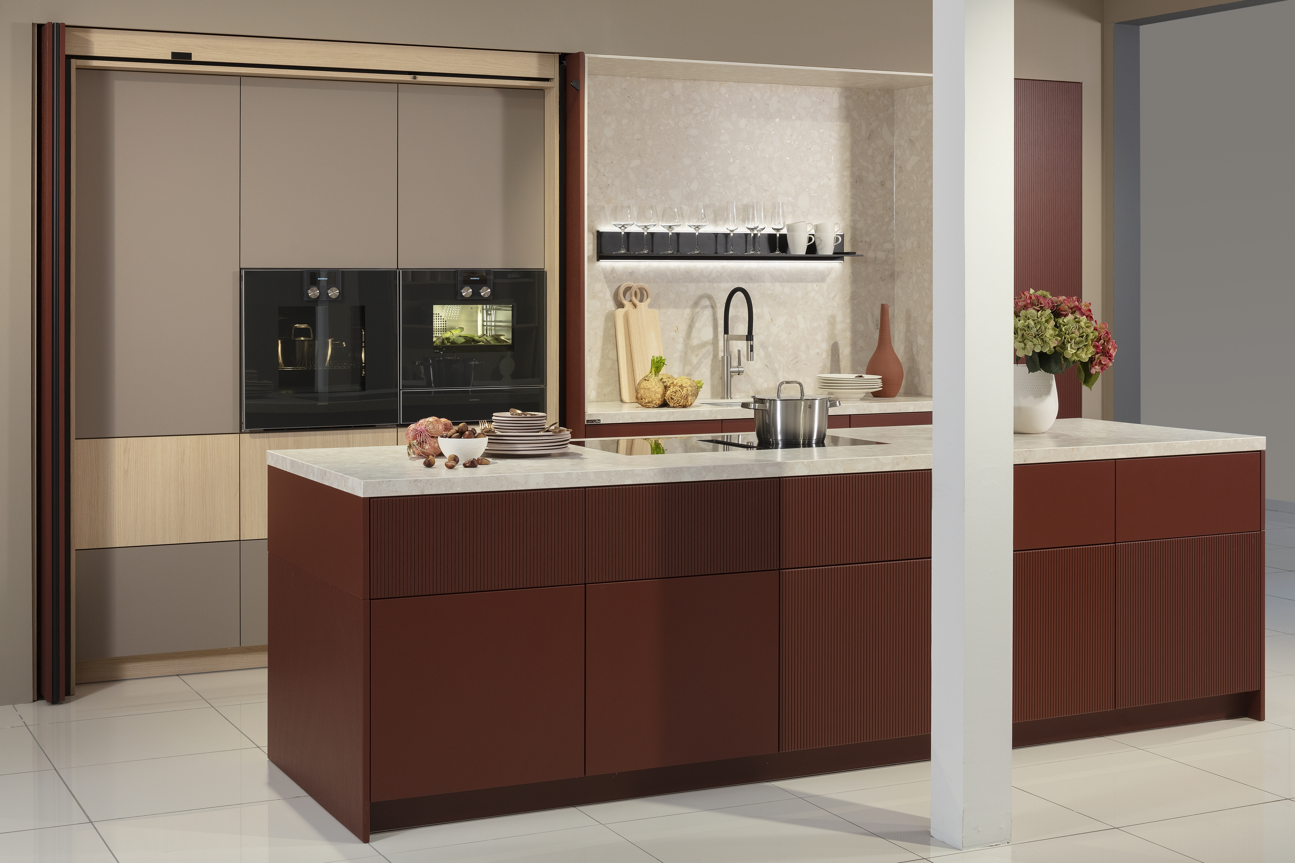 Küchenzeile mit Kücheninsel in Samtlack rot und weißer Arbeitsplatte, mit geöffneter Schrankwand.