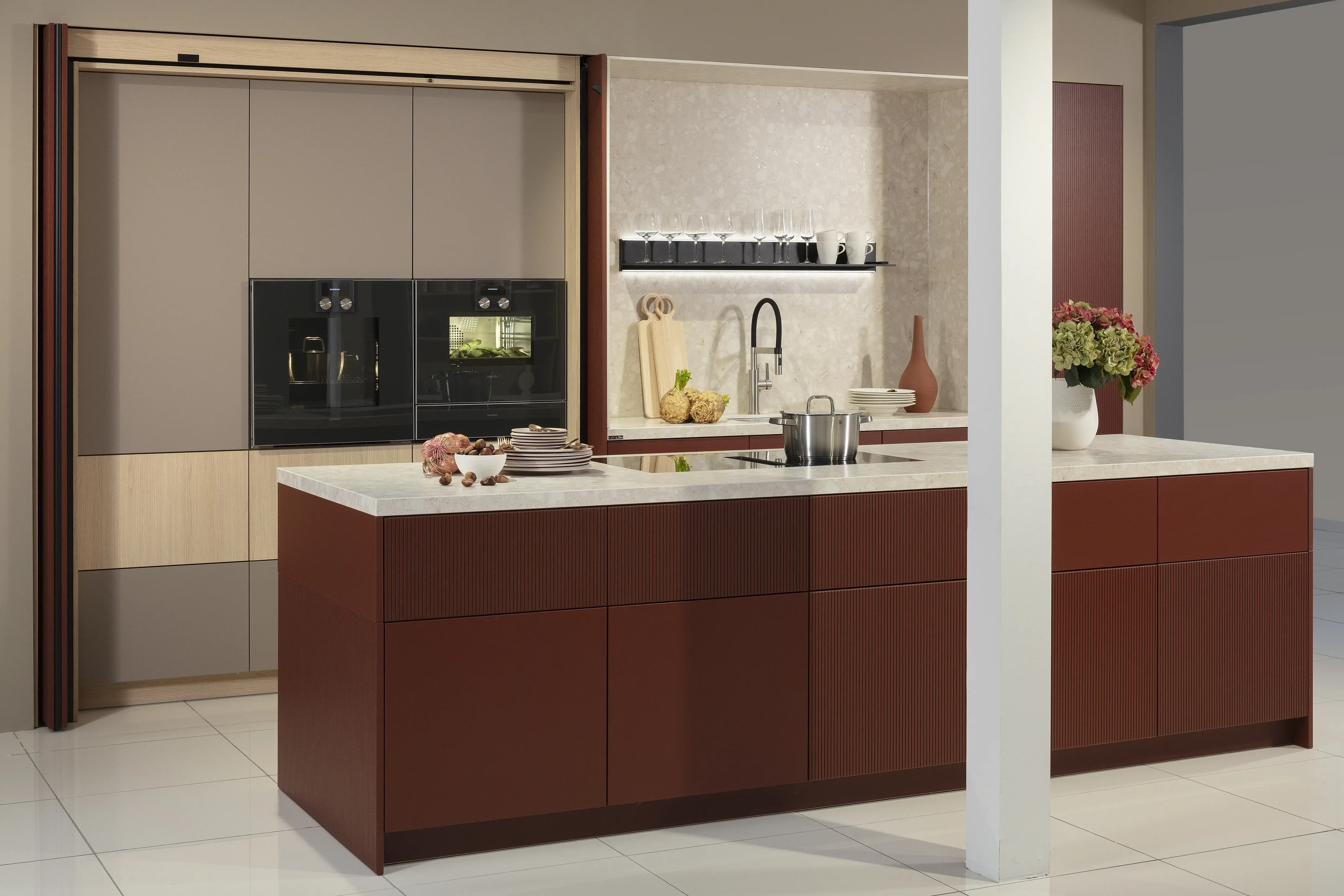 Küchenzeile mit Kücheninsel in Samtlack rot und weißer Arbeitsplatte, mit geöffneter Schrankwand.