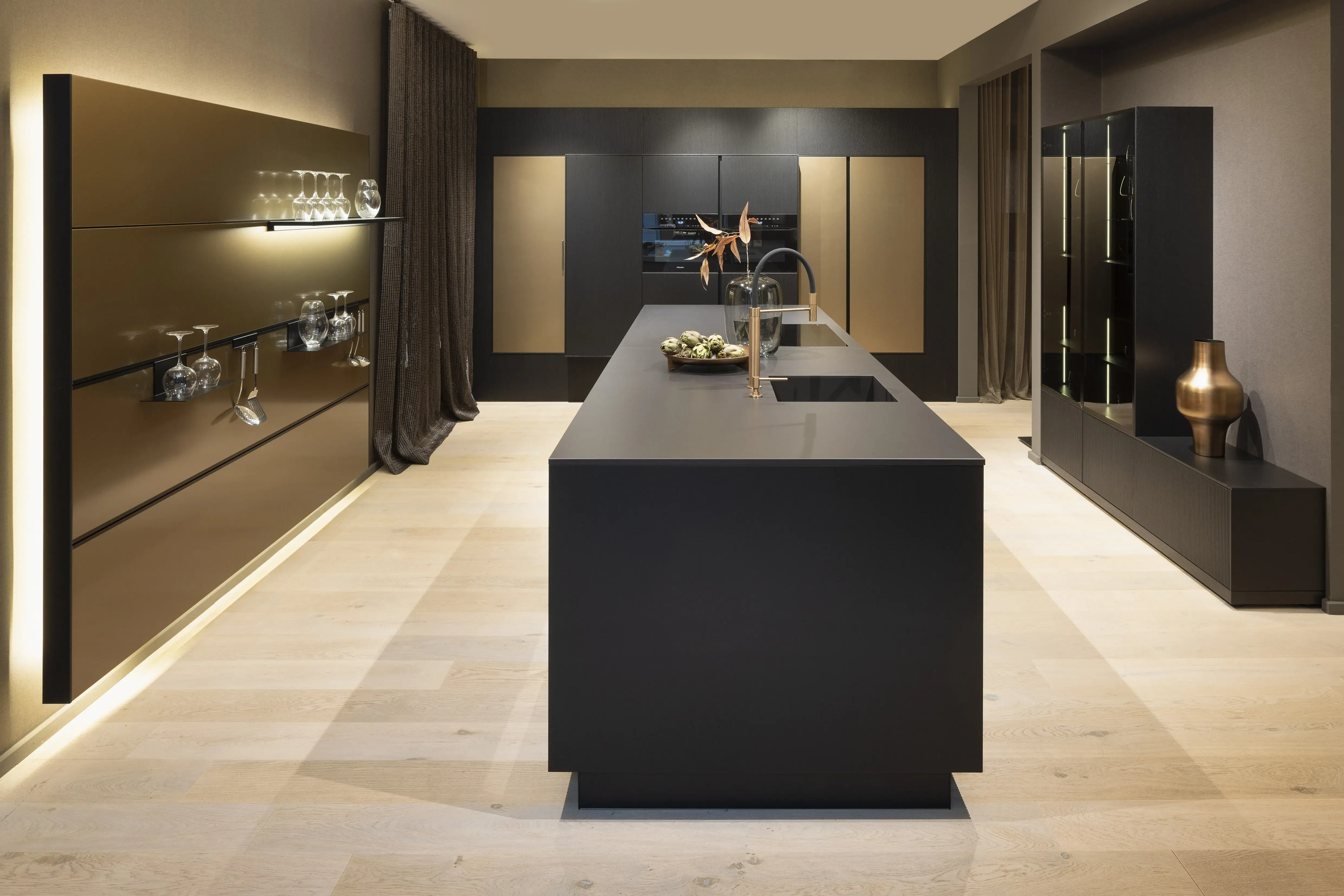 APL: Silk Negro Naturale (Keramik) 16 mm   Front: AV 6023-GL Eiche-schwarz Echtholzfurnier Rille AV 7070 Industriestahl Bronze, Metalliclack Korpus: 4059 Titan Griff: Kehlleiste 355 Schwarz matt Geräte: Miele Armatur: Gessi Features: Regalwandlösung mit beleuchtetem Wandboard, Oberfläche von Hand bearbeitet, Materialmix, Trendthema Bronze, Glasschublade mit Plexiglas in Schwarz getönt, Thekenlösung mittig, Wand aus Oberflächenmaterial in Bronze mit beleuchteten Funktionsleisten für Gläser, etc. 